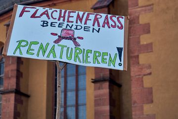 Schild: Flächenfraß durch Straßen beenden! Renaturieren! (Foto: Niko Martin)