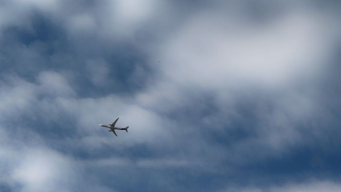 Flugzeug vor Wolken am Himmel