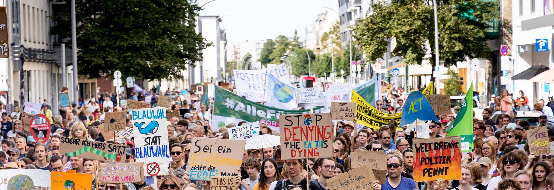 Menschen laufen in einem Demozug und halten Schilder hoch